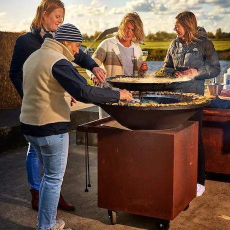 Vier Frauen grillen gemeinsam an einem Classic Corten Feuerring im Freien