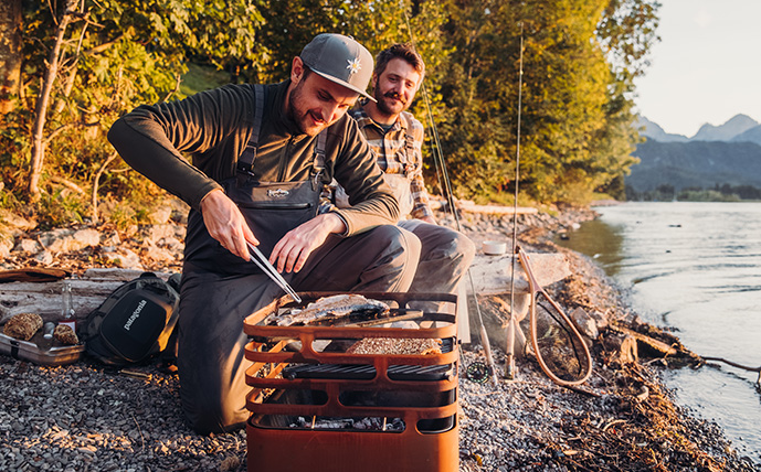 der-feuerkorb-cube-aus-cortenstahl-im-einsatz-beim-fischgrillen-am-fluss