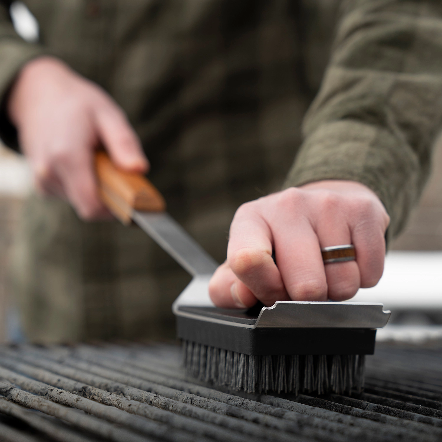 mit-einer-grillreinigungsbürste-wird-ein-grillrost-gesäubert.