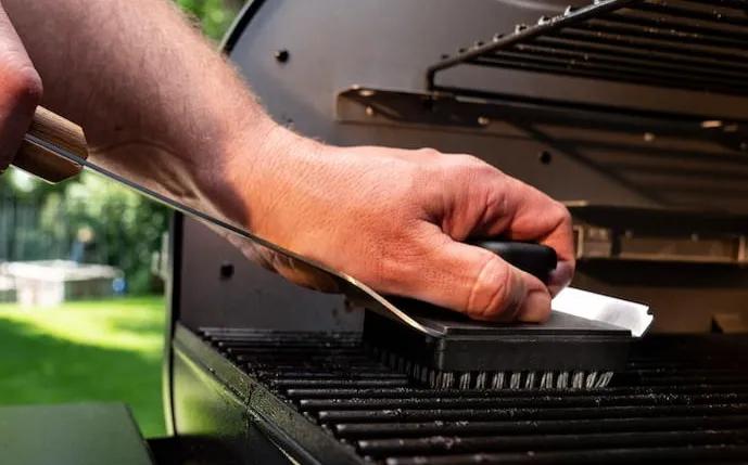 hand-mit-einer-grillreinigungsbürste,-die-ein-rost-säubert