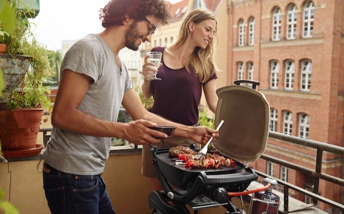 junge-leute-auf-einem-balkon-mit-einem-weber-gaskugelgrill