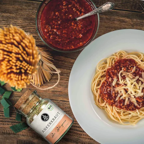 Teller mit Spaghetti Bolognese, einer Gewürzmischung und einem Topf mit Sauce