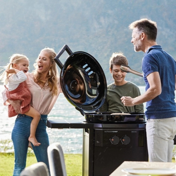familie-mit-zwei-kindern-an-einem-geöffneten-kugelgrill