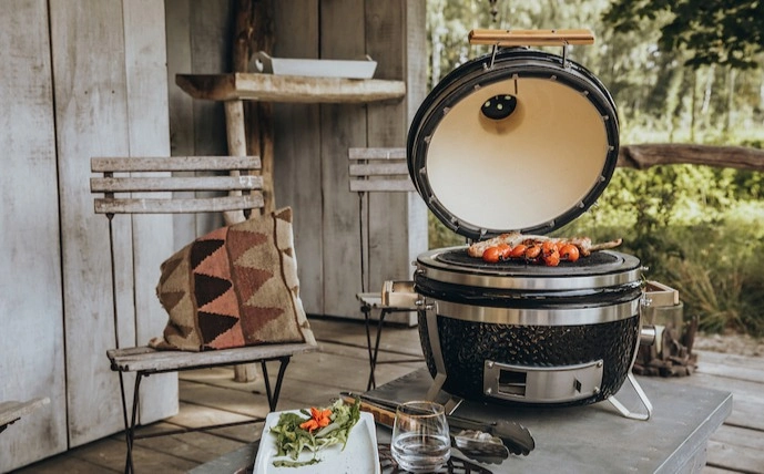 monolith-icon-keramikgrill-auf-einem-tisch-mit-fleisch-und-tomaten-auf-einer-terrasse