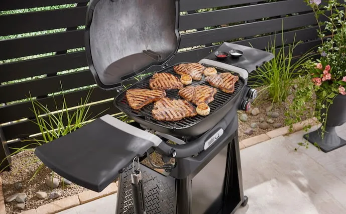 weber-gasgrill-der-q-serie-in-aktion-mit-fleisch-auf-dem-rost-in-einem-garten