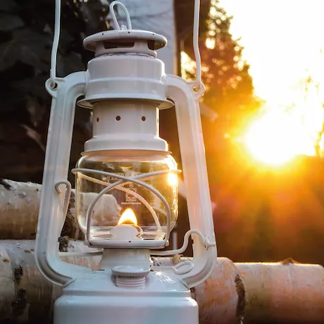 Eine weiße Feuerhand-Sturmlaterne, die im Sonnenuntergang leuchtet.