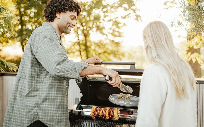 mann-und-frau-an-einem-gasgrill-mit-drehspieß
