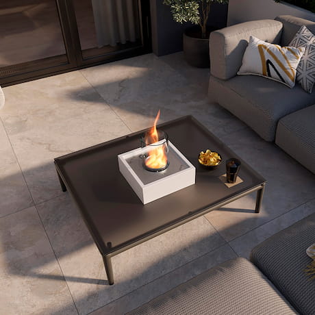 Ein kleiner, weißer Tischkamin auf einem Tisch auf einer Terrasse