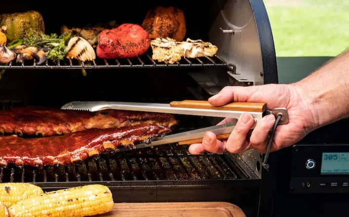 große-grillzange-hält-ein-stück-fleisch