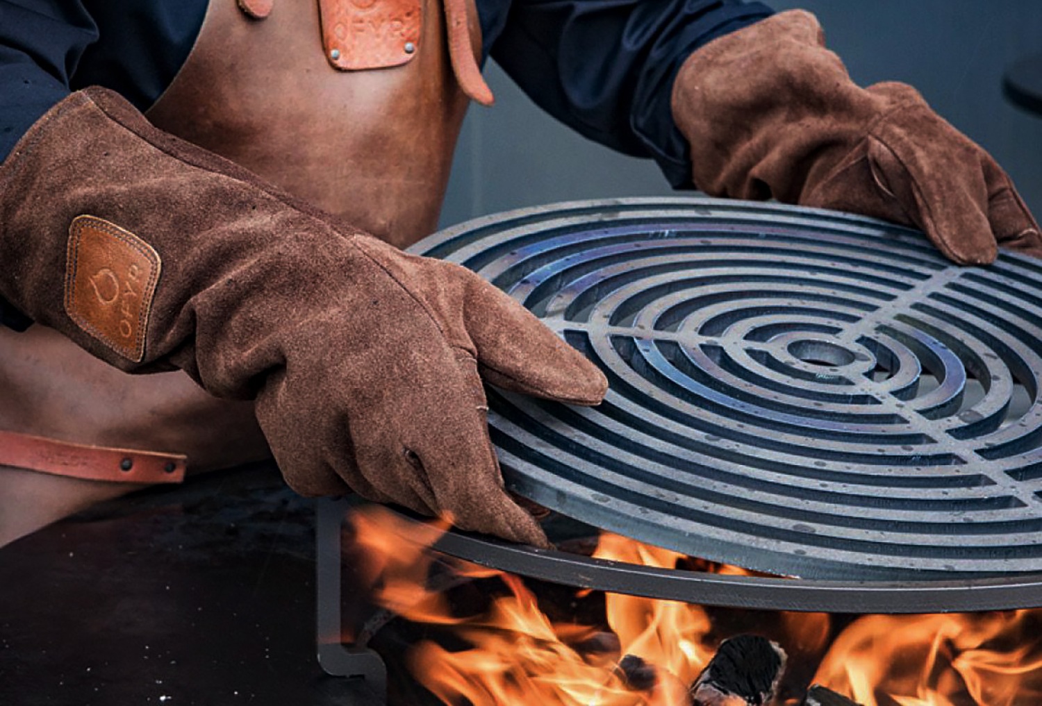 ofyr-grillhandschuhe-setzen-einen-grillrost-über-dem-feuer-ein