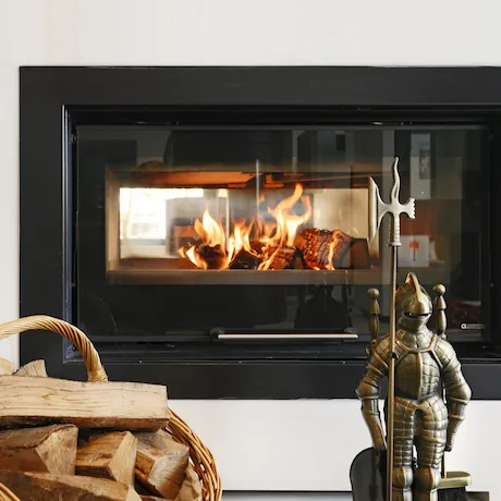 Kamin mit Feuerholz drinnen und Ritterstatue und Holzhaufen davor